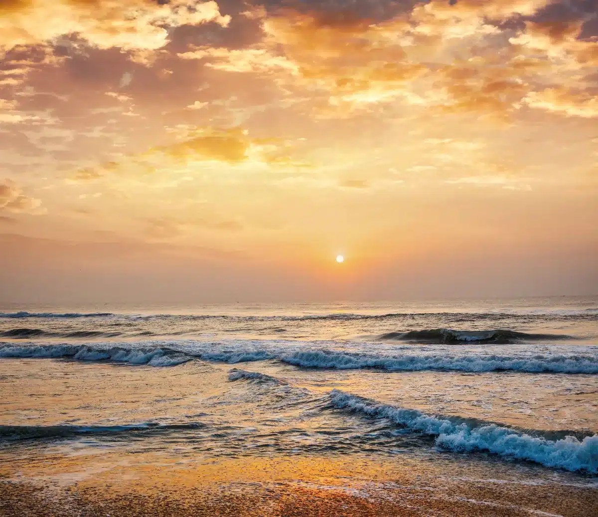 The sun rising over gentle ocean waves